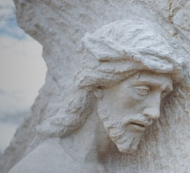Close-up of a sculture of Jesus Christ carrying a large cross.  Image by Wesley Tingey on Unsplash.