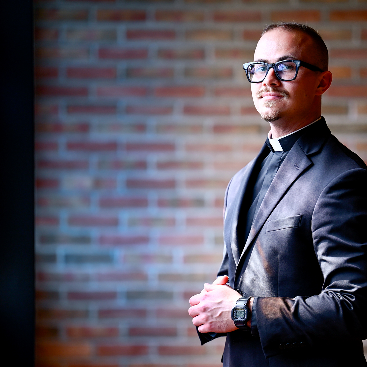 Portrait of a young priest standing with their hands together