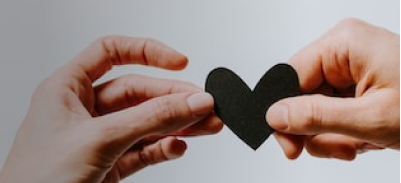 Two people each holding a side of a paper heart.  Image by Kelly Sikkema on Unsplash.