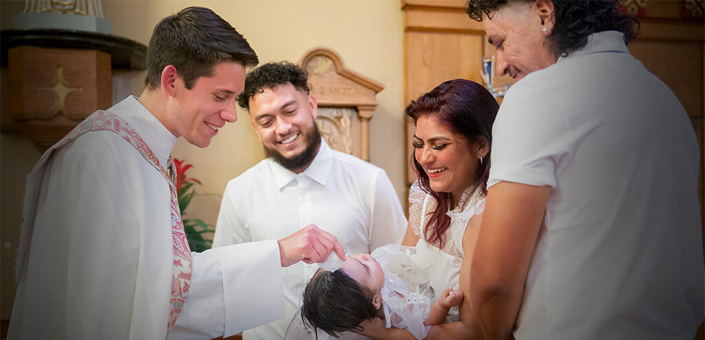 Smiling Deacon Jeremy Leganski performing a baptismal